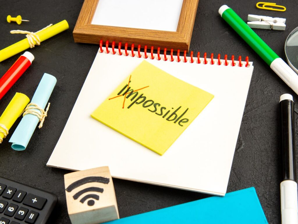 Escritorio académico con nota amarilla que dice 'Impossible' tachado, simbolizando que hacer un TFG en una semana es posible.